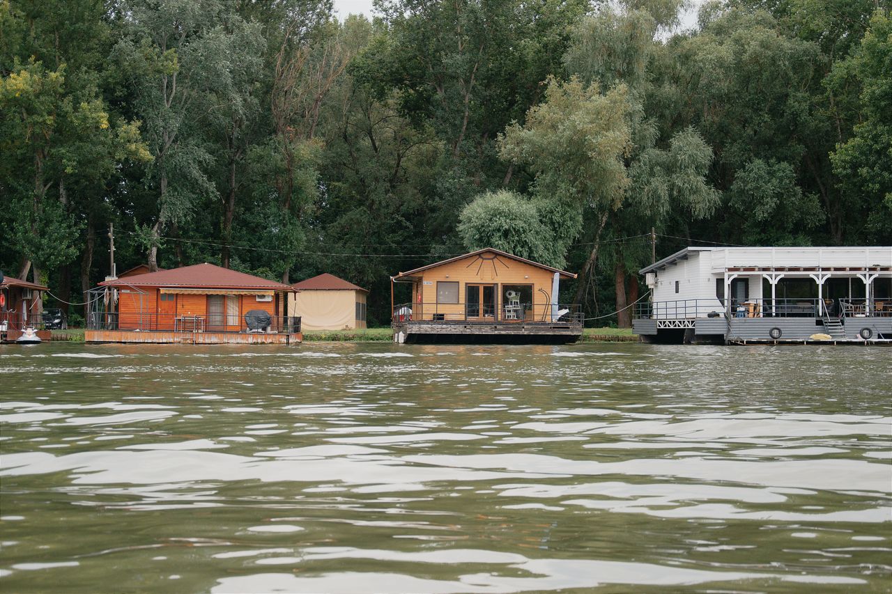 tranquil scene of floating boathouses on a lake in hungary surrounded