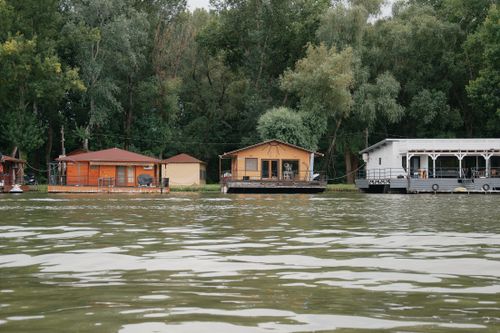 Free Tranquil scene of floating boathouses on a lake in Hungary surrounded by lush greenery. Stock Photo