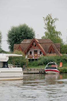 Rustic lakeside house with boats on a calm summer day in Hungary.