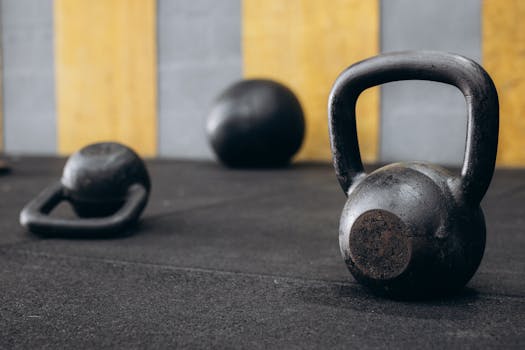 Close-up of black kettlebells on gym floor, emphasizing strength and fitness.
