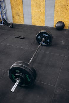 A heavy barbell rests on a gym floor, ideal for strength and weightlifting exercises.