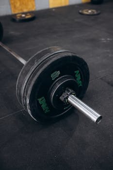 Close-up of a heavy barbell with weight plates on a gym floor, ideal for strength training and bodybuilding.