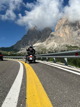 Motorcyclist travels through stunning mountain landscape in Dolomites, Italy.