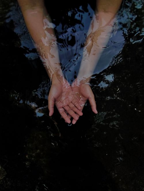 Free Hands reaching out in dark water, creating a moody reflection effect. Stock Photo