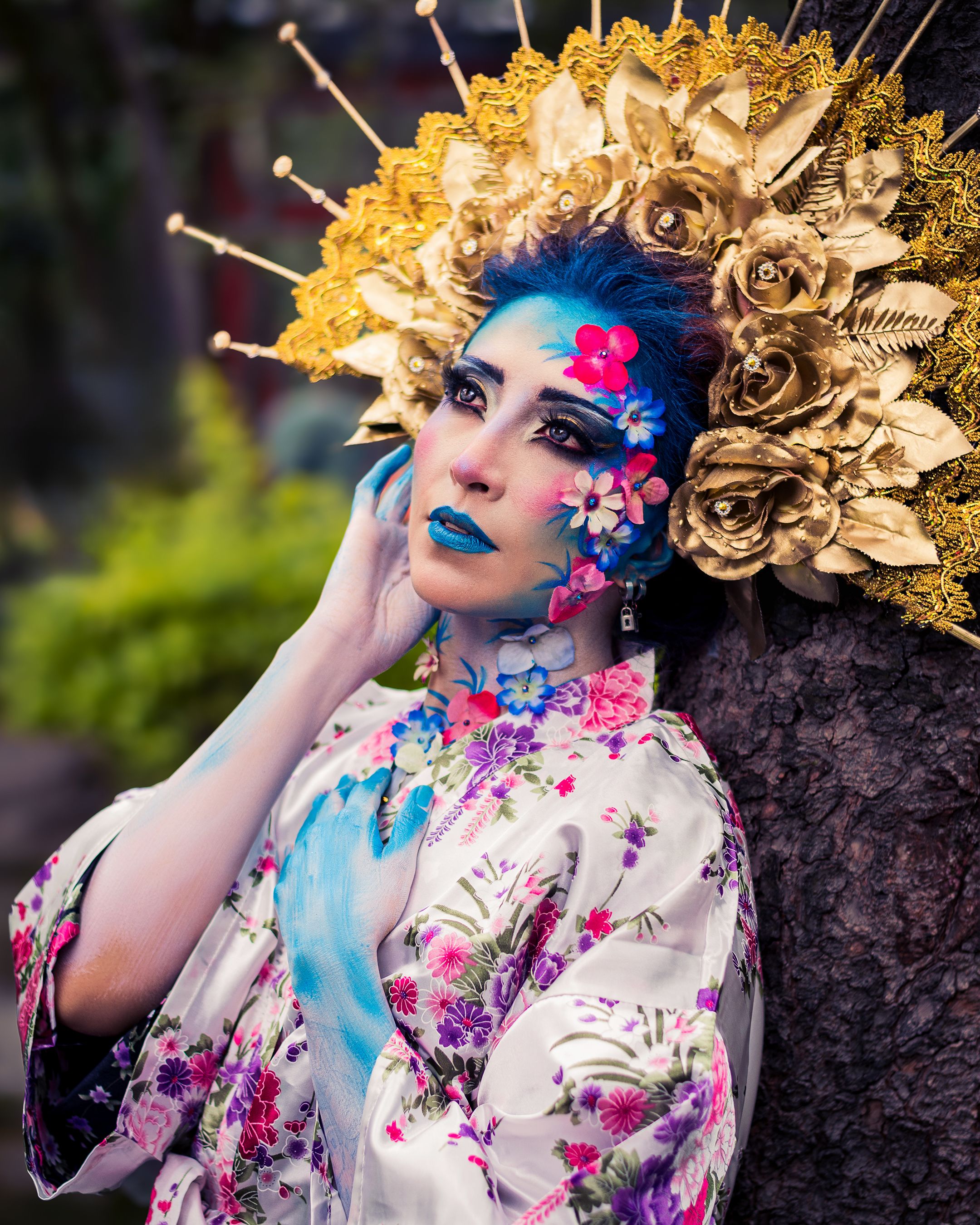 Striking portrait of a woman in a vibrant costume with a floral headpiece and blue makeup.