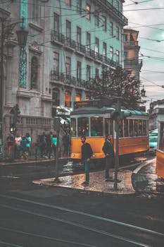 A classic yellow tram navigating through the streets of Lisbon, Portugal, showcasing urban transportation.
