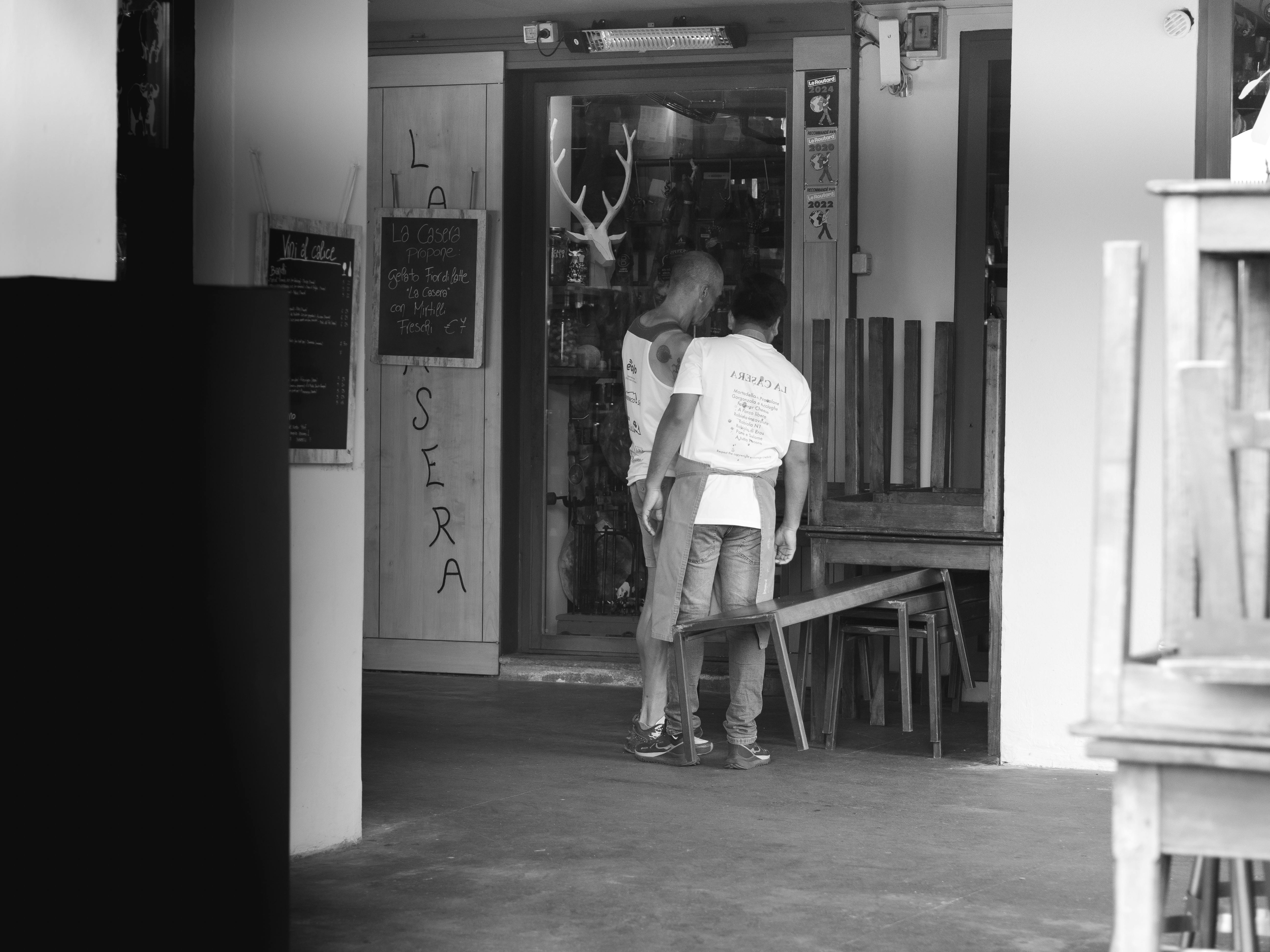 a black and white photo of two people standing in front of a store