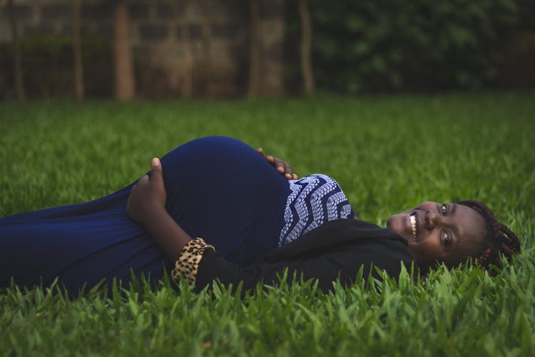 Pregnant Woman Lying On Green Grass Fields