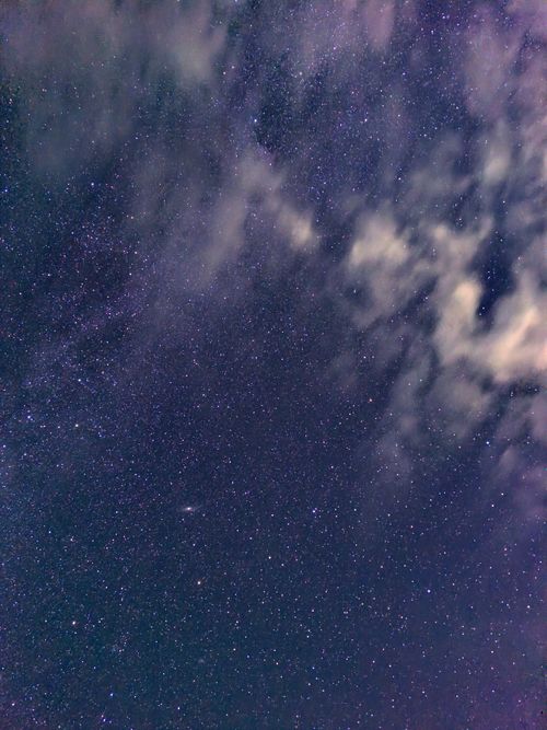 Free A mesmerizing view of a starry night sky with scattered clouds. Stock Photo