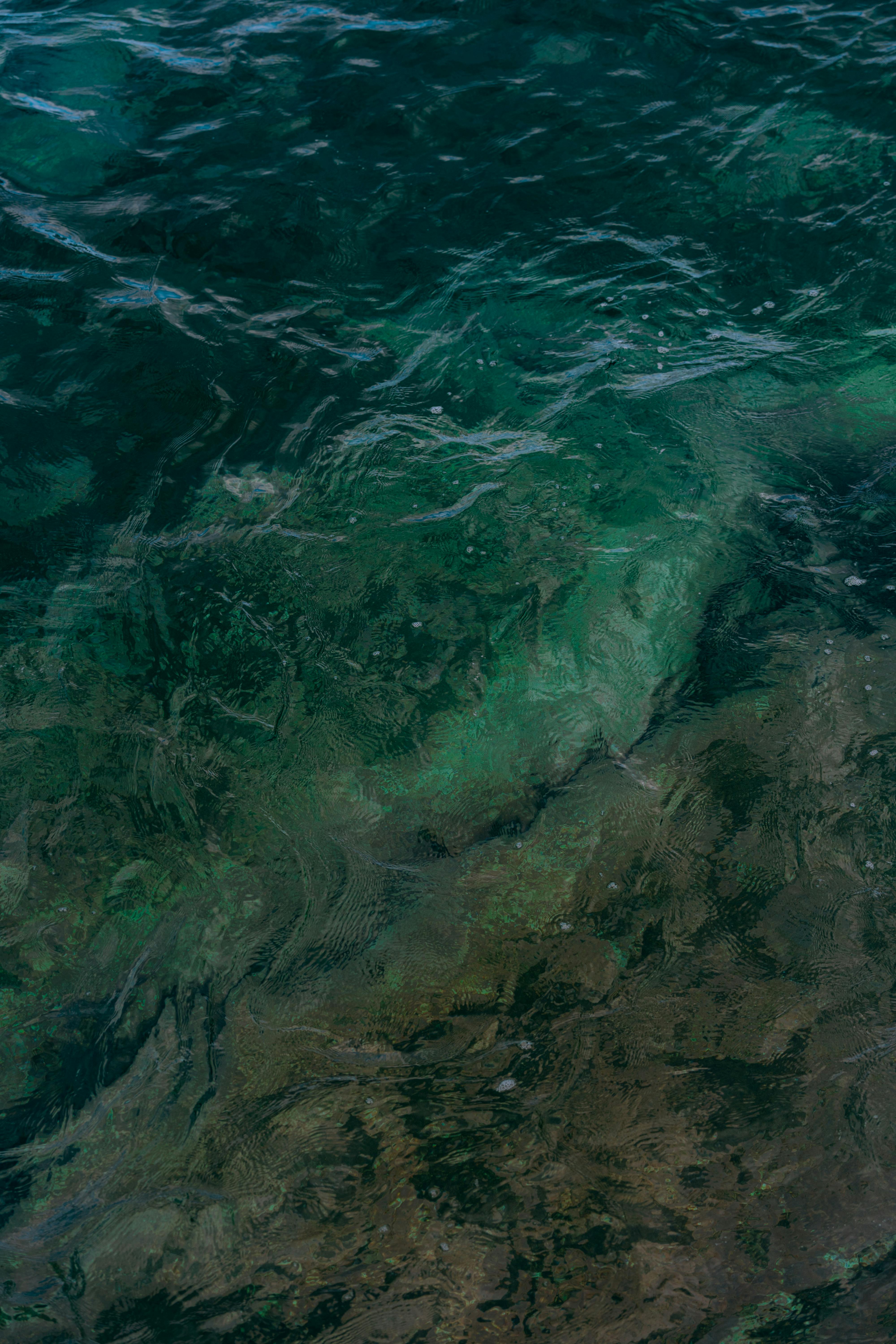 A stunning view of clear turquoise water with visible rocky ocean floor, creating abstract patterns.