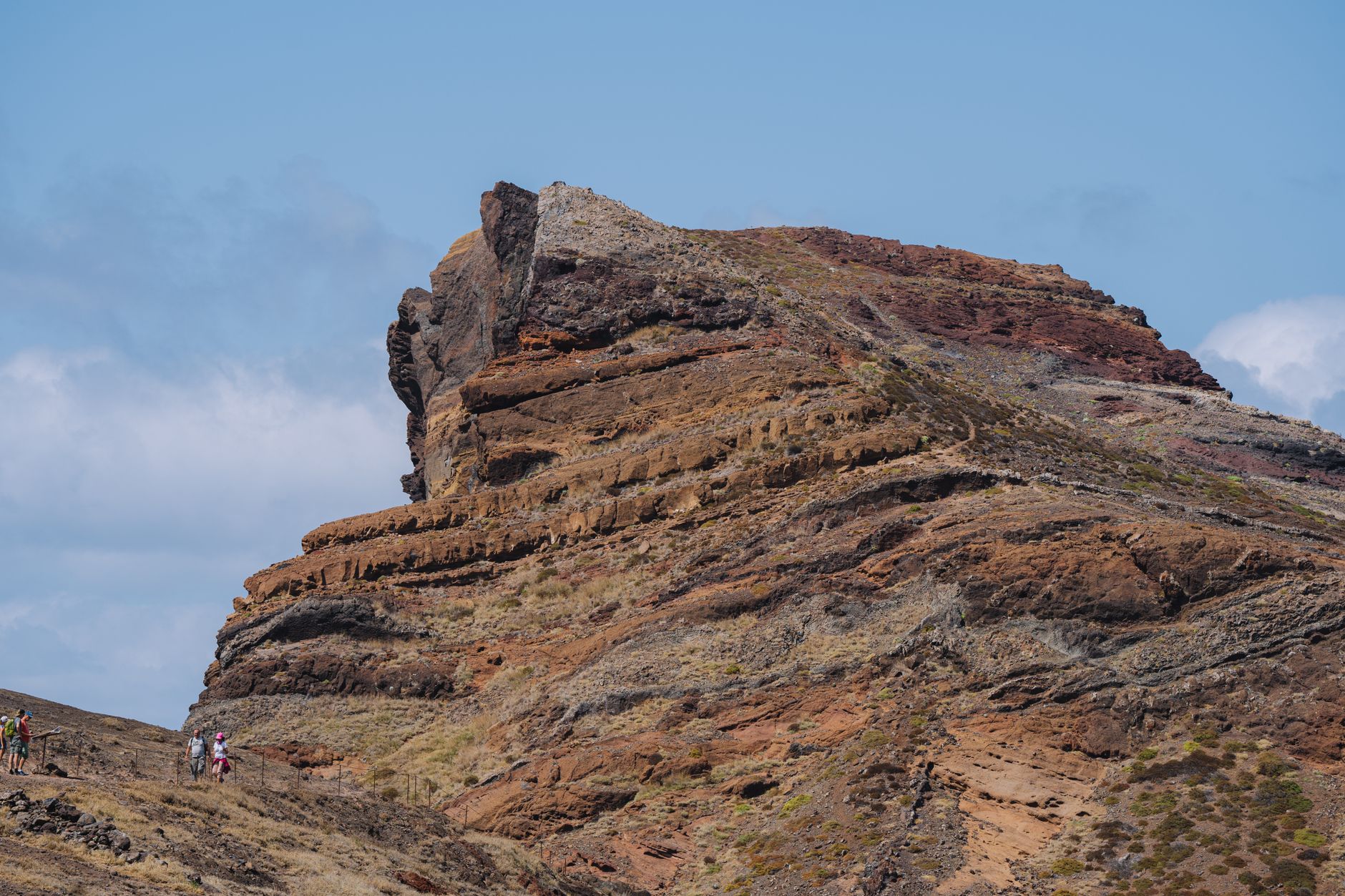 Explore a stunning rocky mountain landscape with hikers at Cape Verde, under a bright blue sky.