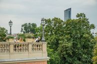 Relaxing scene in Wrocław's park with modern skyscraper in view.