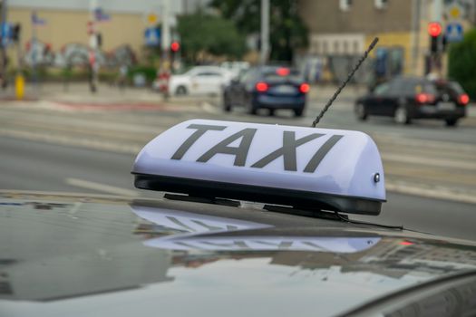 Taxi sign on a car roof with urban traffic in Wrocław, Poland.