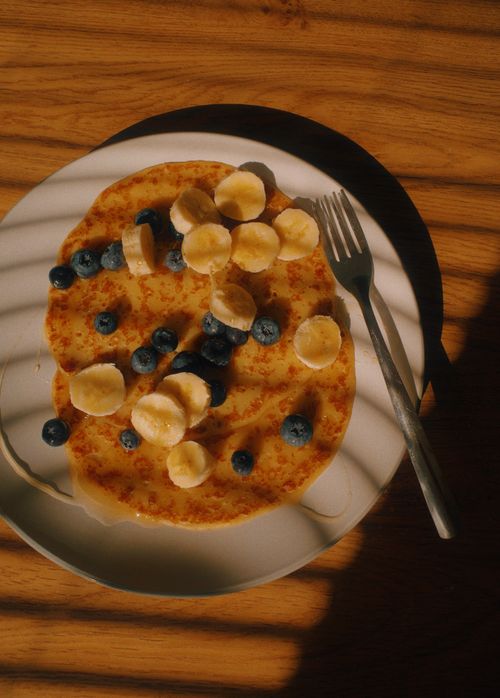 Free Delightful pancake served with fresh bananas and blueberries, perfect breakfast choice. Stock Photo