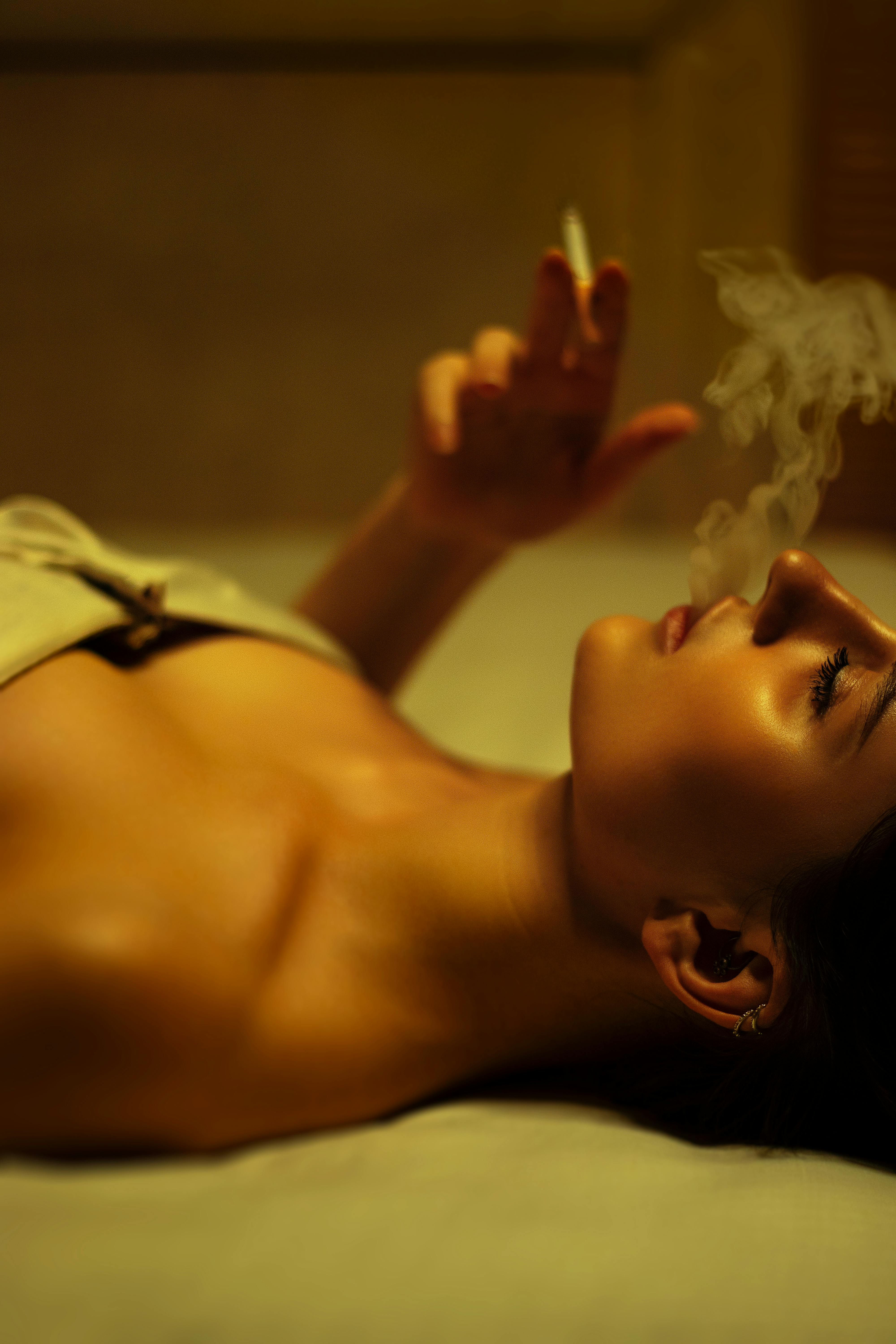 a woman laying on a bed smoking a cigarette