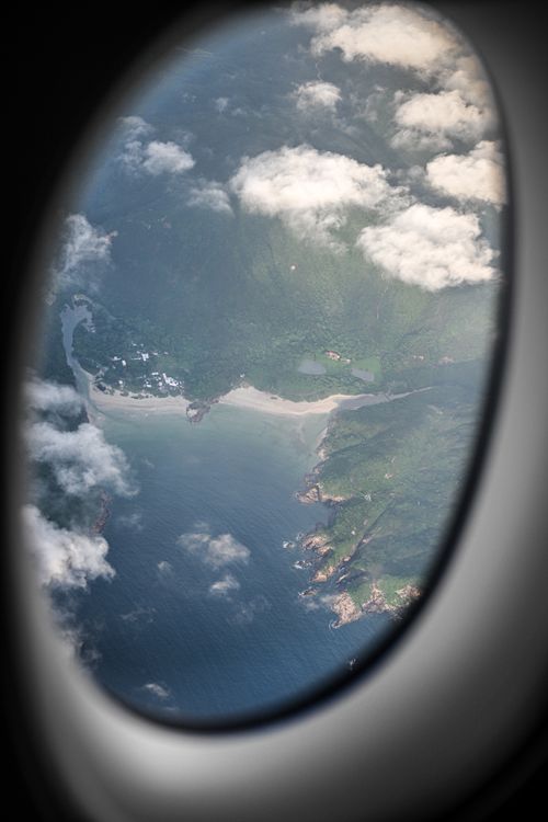 Free A stunning view of a Hong Kong beach captured through an airplane window, showing lush landscapes and the sea. Stock Photo