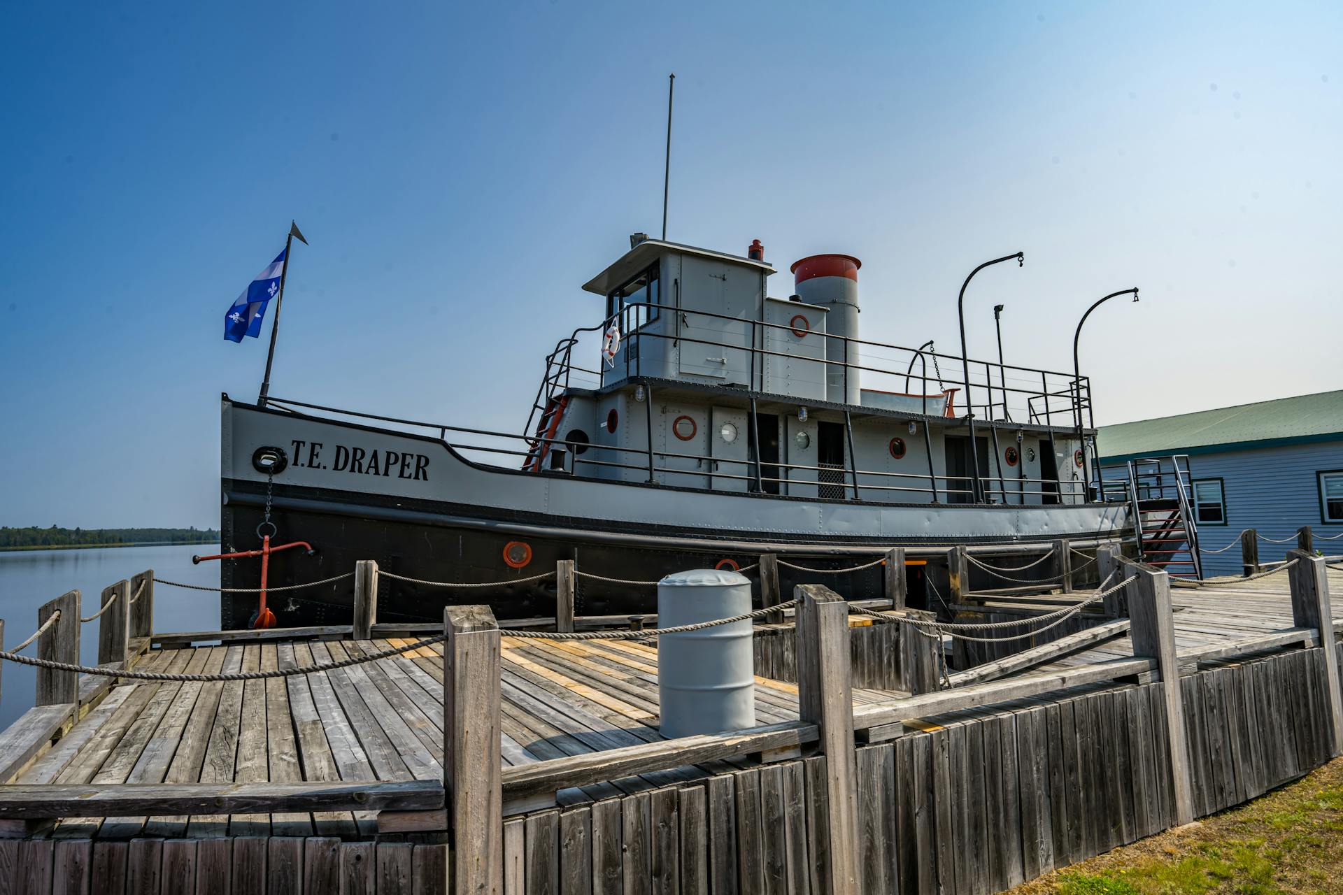 A vintage tugboat named T.E. Draper docked at a pier in Angliers, Canada, on a sunny day.