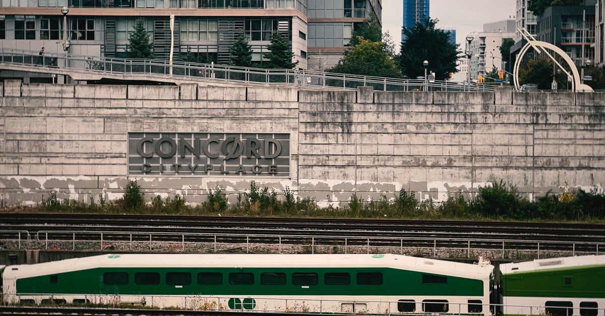 Green train in urban area near Concord Cityplace buildings, showcasing modern architecture and transport.