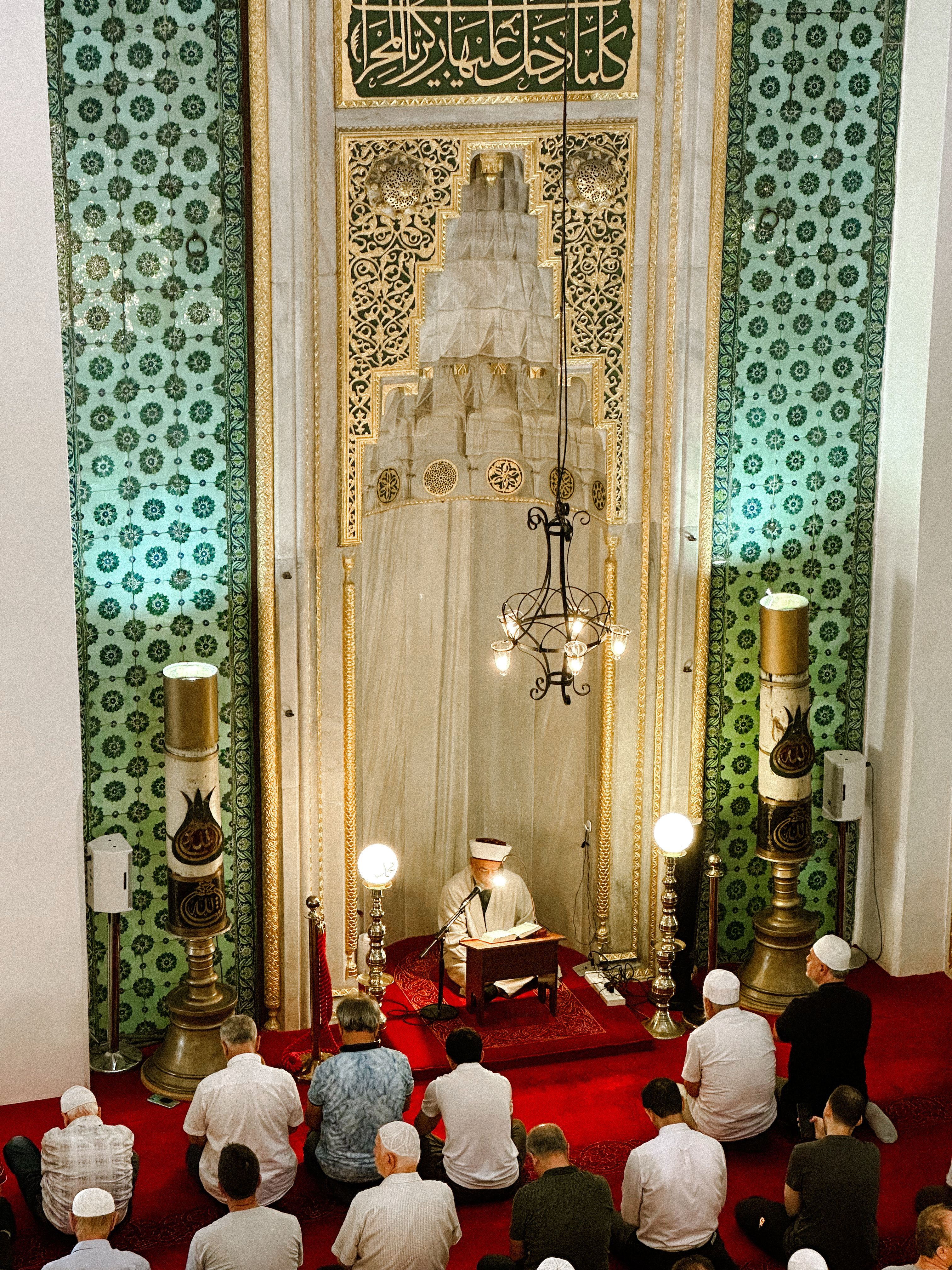 Worshipers in a beautifully ornate mosque interior during a spiritual gathering.