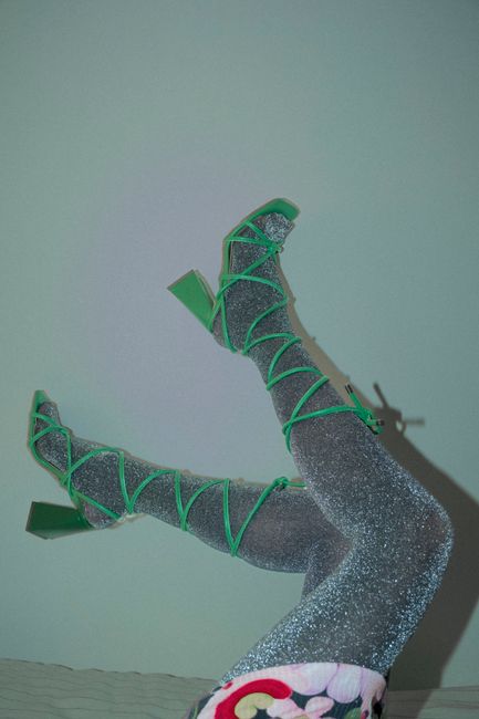 A creative fashion shot featuring green heels and glittery hose, emphasizing style and modern design.