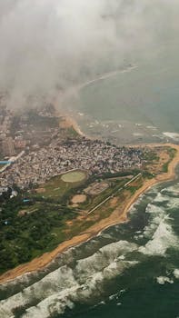A stunning aerial view of Visakhapatnam's coastline with waves and cityscape on a cloudy day.