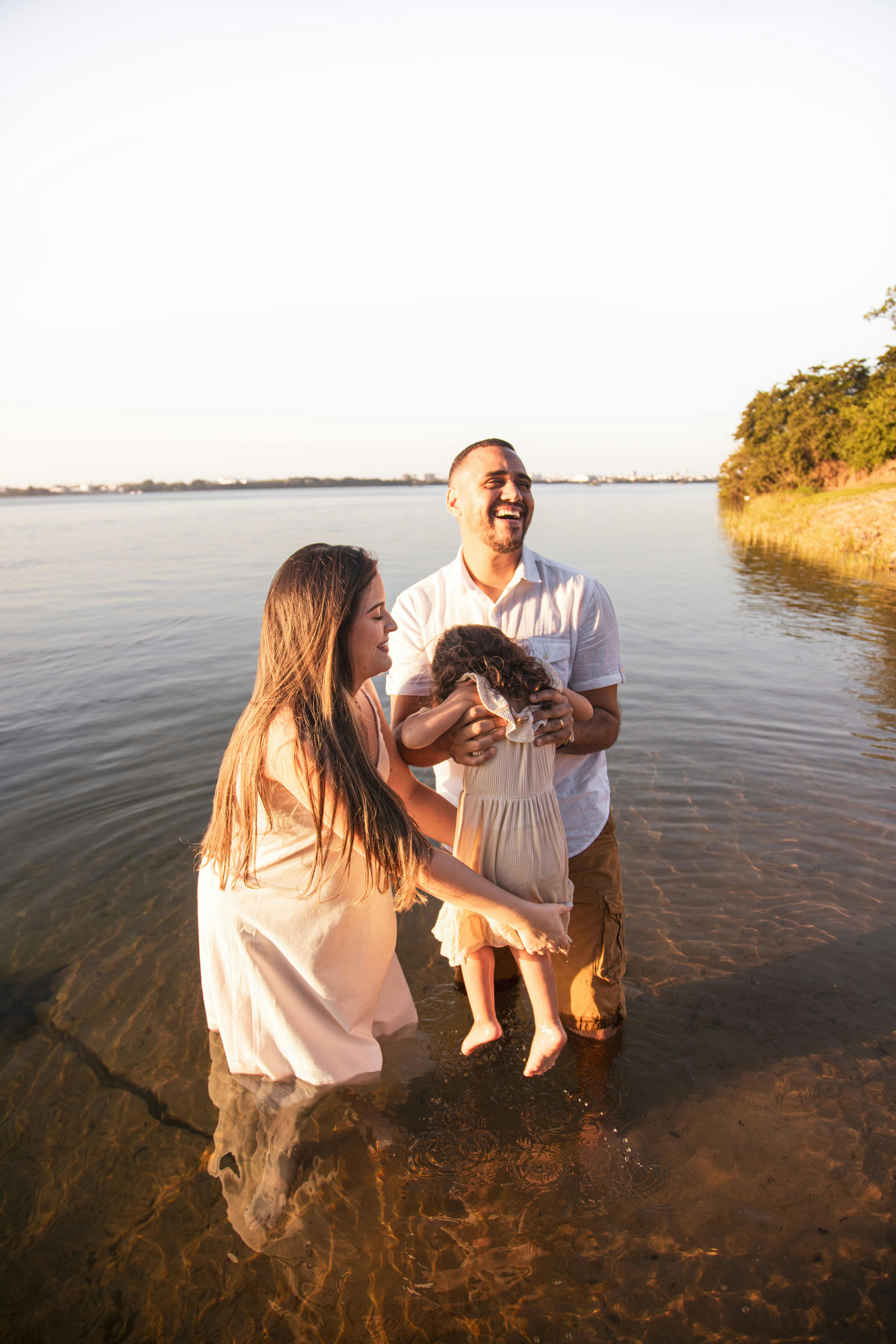 a family is standing in the water with their daughter