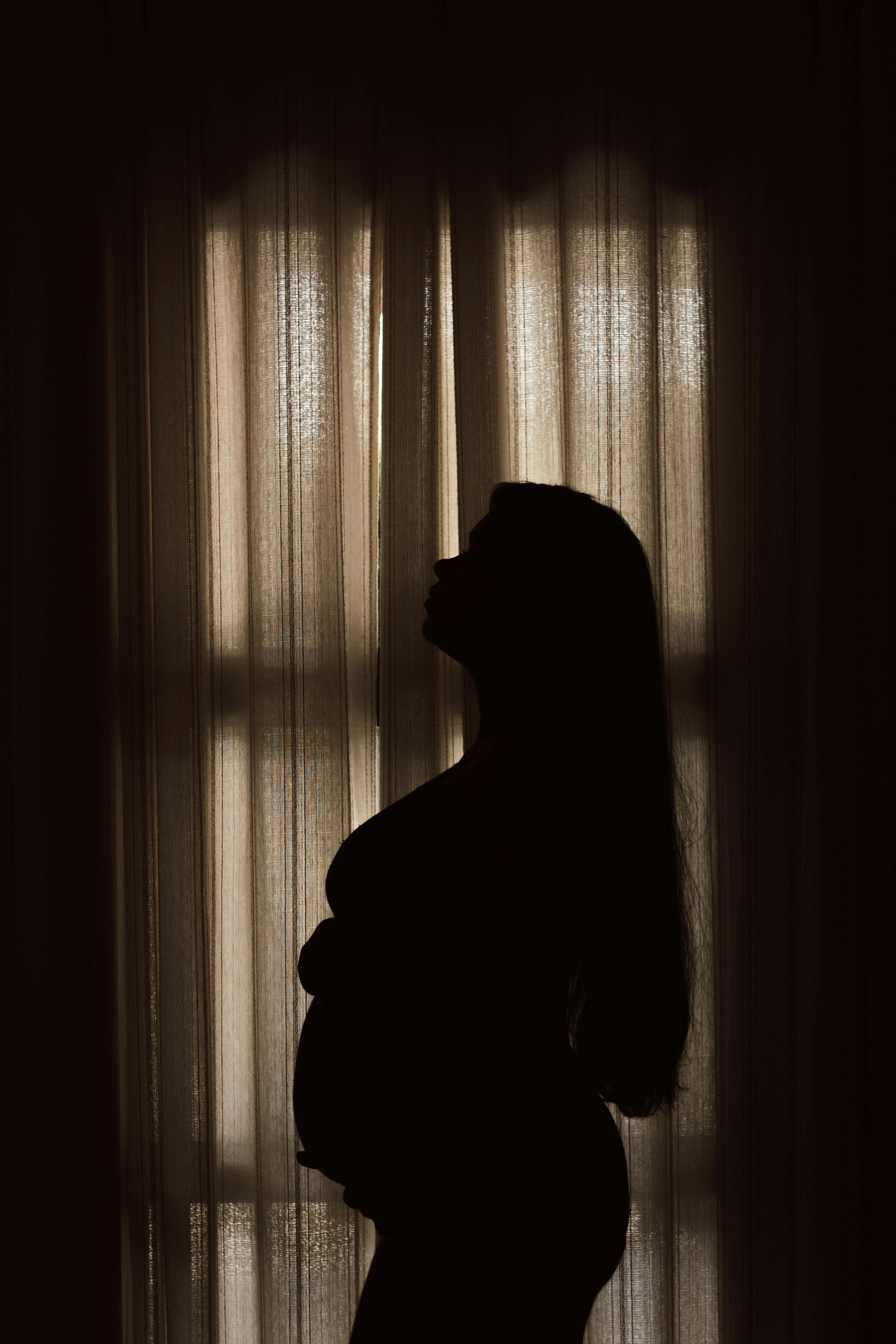 a pregnant woman standing in front of a window