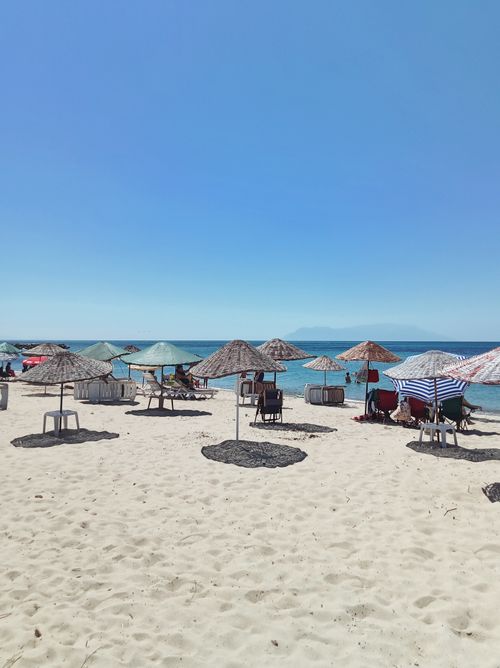 Free Relaxing day on a sandy beach in Edirne, Türkiye, with umbrellas overlooking the turquoise sea. Stock Photo
