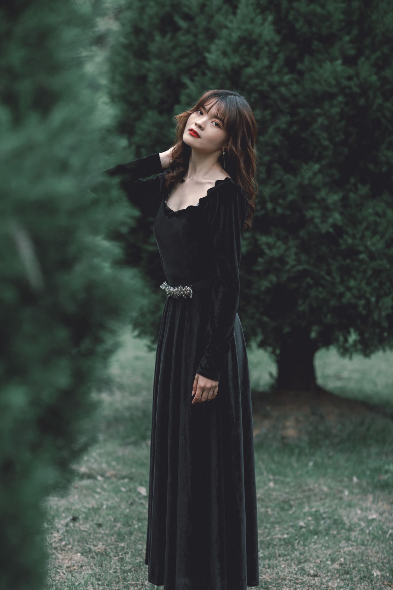 Woman in a long black velvet dress with a jeweled belt outdoors