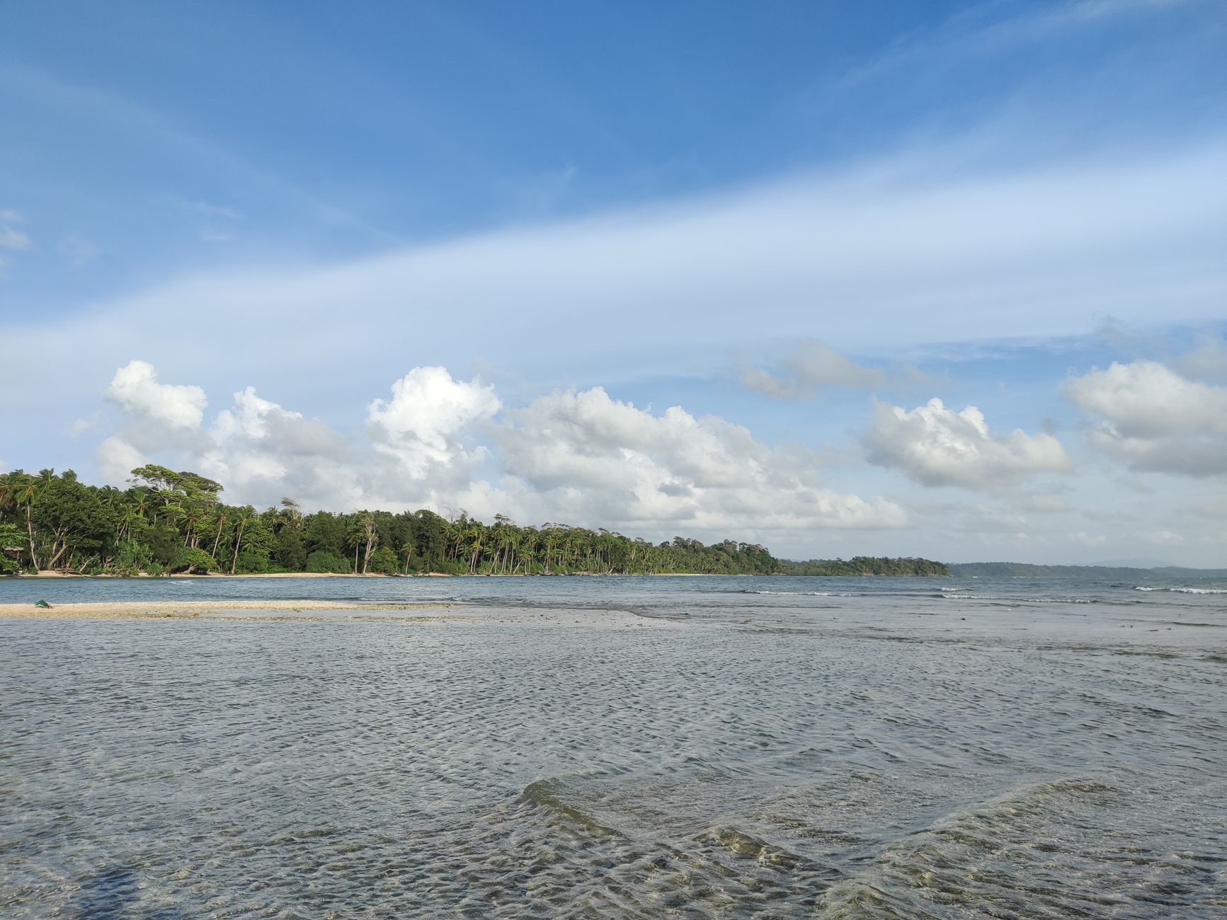 Tranquil beachfront landscape in Andaman with clear skies and lush greenery.