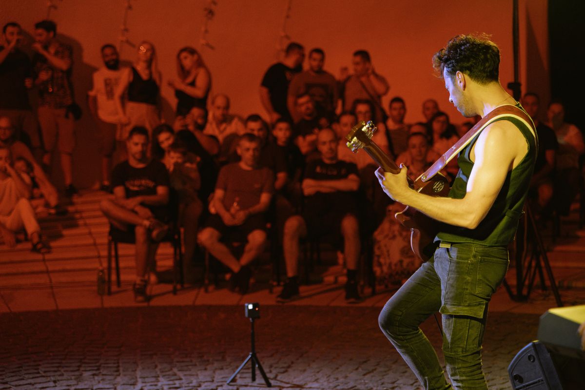 A guitarist performing on stage in front of a crowd