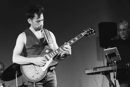Black and white photo of a guitarist playing electric guitar during a live performance.