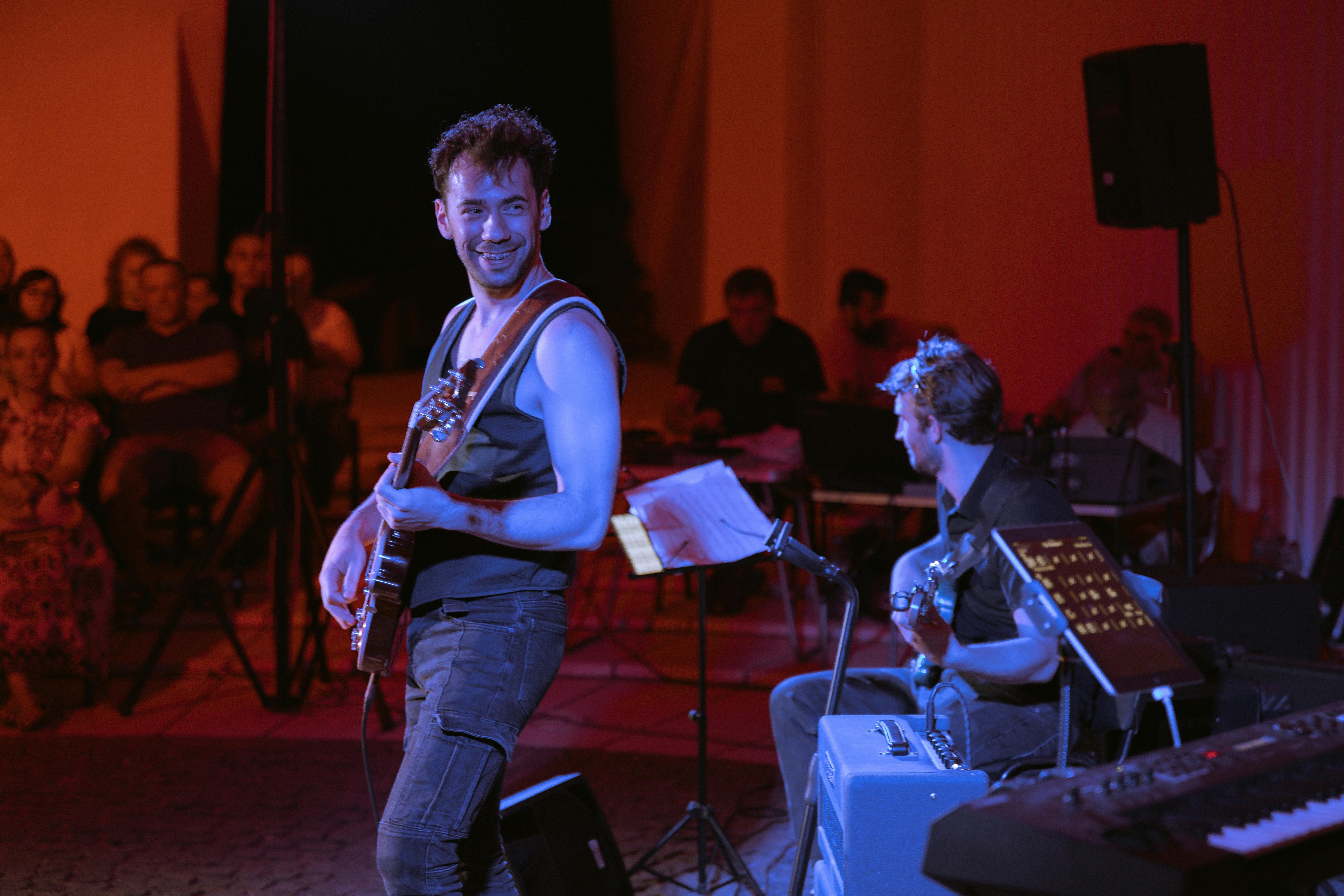 a man playing guitar in front of a crowd