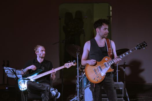 Dynamic live rock performance with musicians playing guitar and bass on stage.