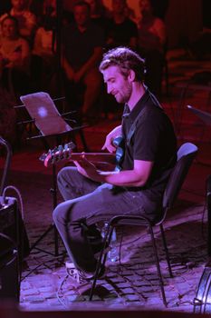 Talented guitarist playing at a lively outdoor night concert, creating a vibrant musical atmosphere.