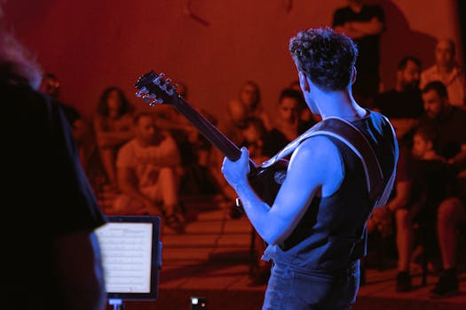 A guitarist performs live in an outdoor music concert at night.
