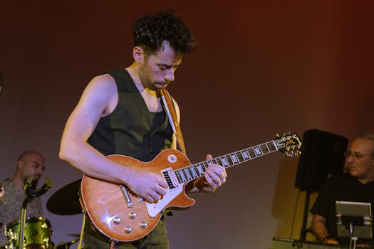 A guitarist passionately playing electric guitar on stage during a live music performance.