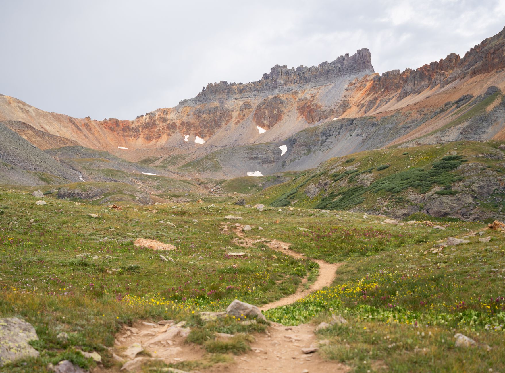 A hiking trail climbing toward a mountain valley in the San Juan National Forest.