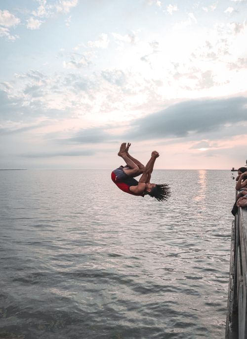 Free Man doing a backflip into the ocean from a pier in Puerto Colombia during sunset. Stock Photo