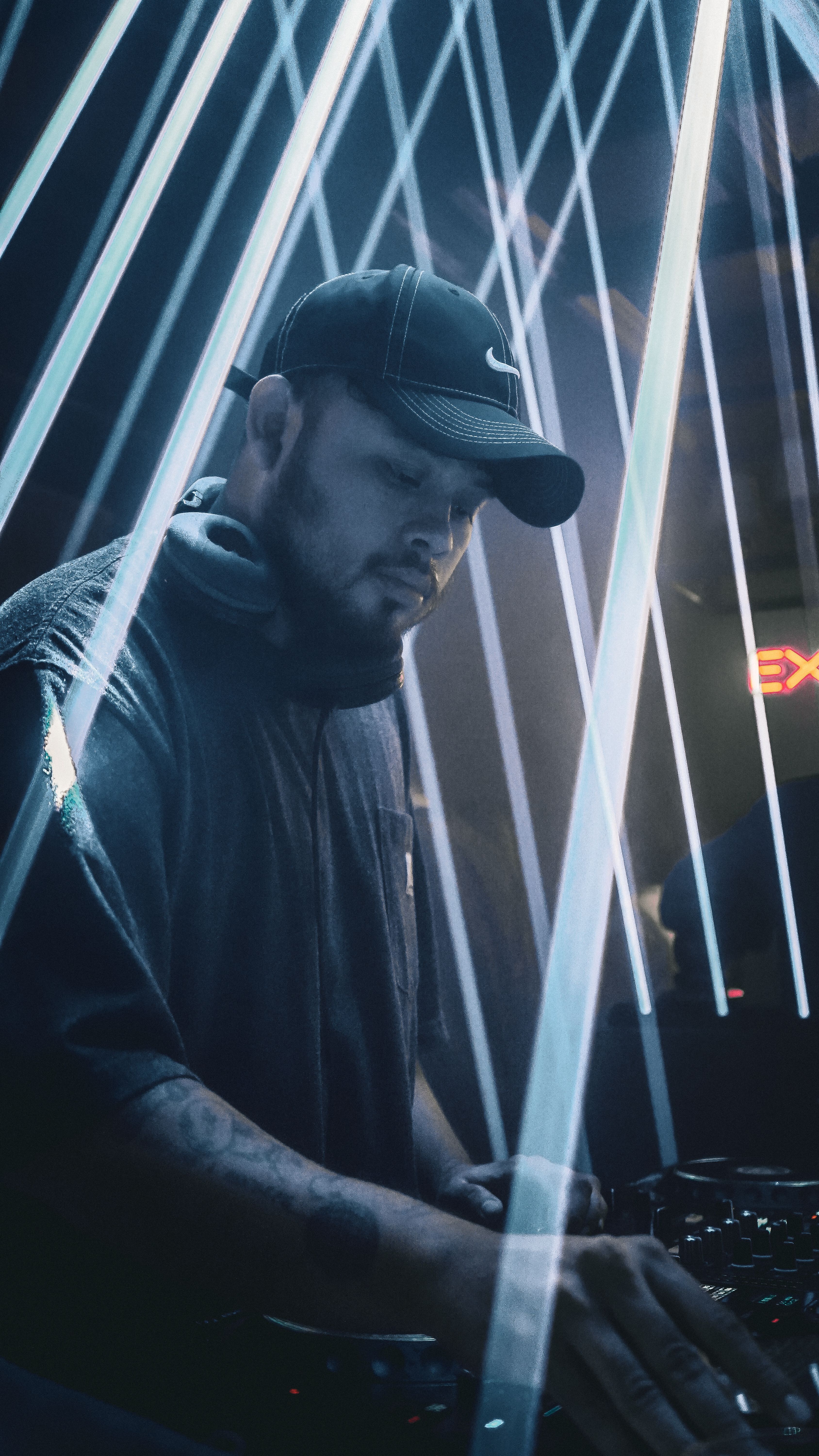 DJ immersed in electronic music under dynamic laser beams at a nightclub.