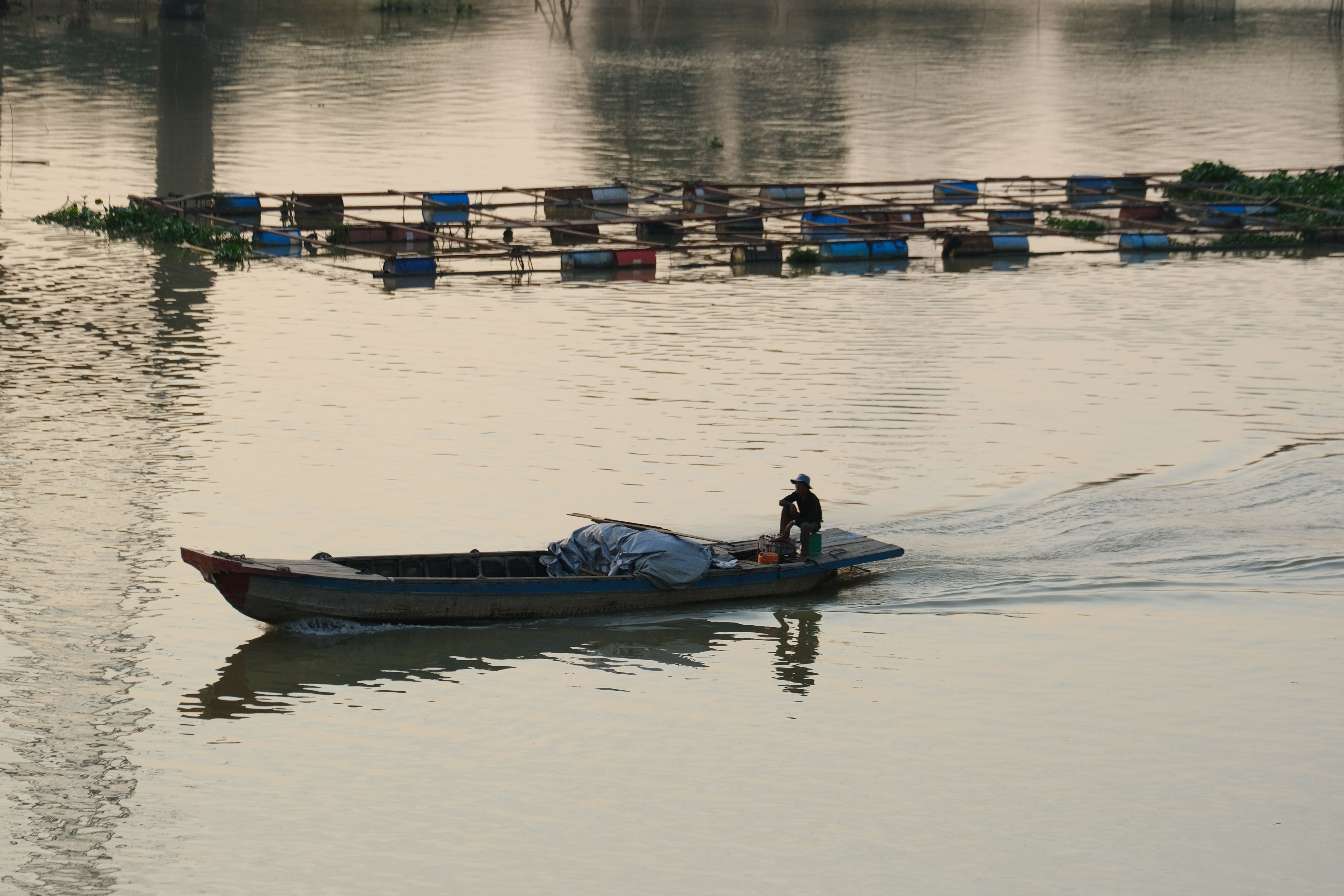 Pescador navegando en bote sobre un río al atardecer