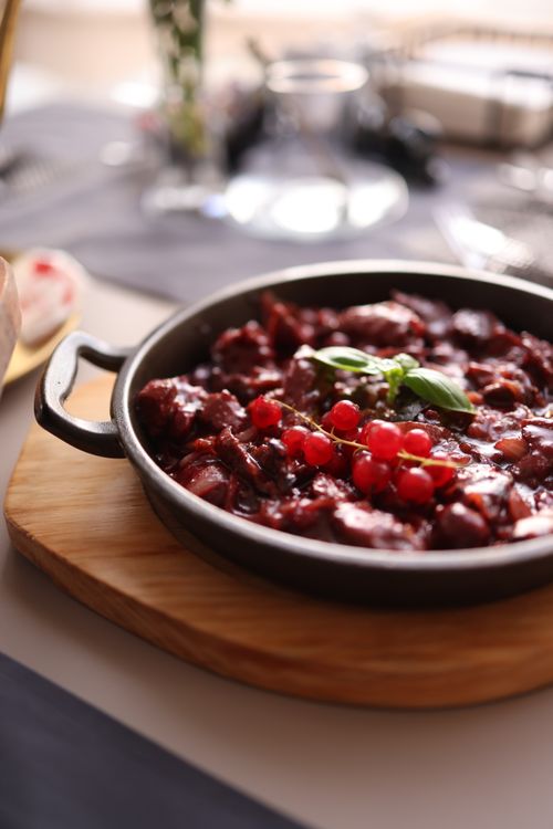 Free Delicious gourmet stew garnished with fresh red berries served in a rustic pan. Stock Photo