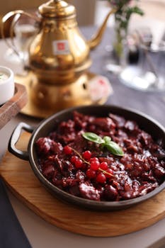 A gourmet dish garnished with berries, set in a rustic ambiance with a brass teapot.