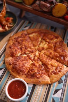 Delicious cheesy pizza served with a side of tangy tomato sauce, perfect for a savory meal.