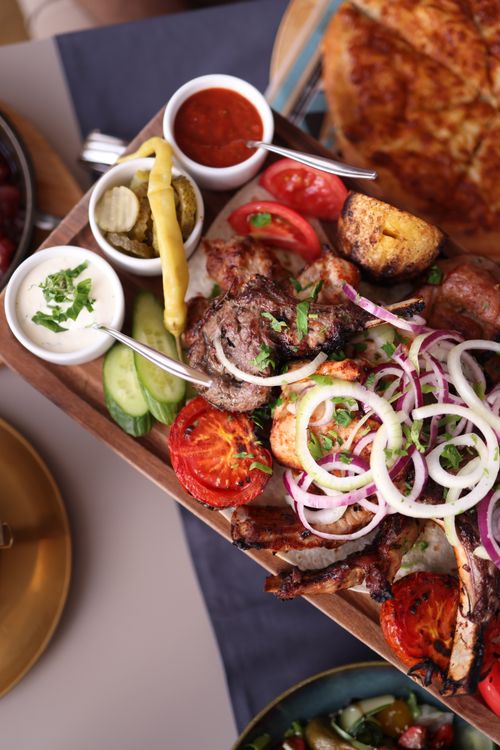 Free Savory grilled meat with fresh vegetables on a rustic platter, perfect for any meal. Stock Photo