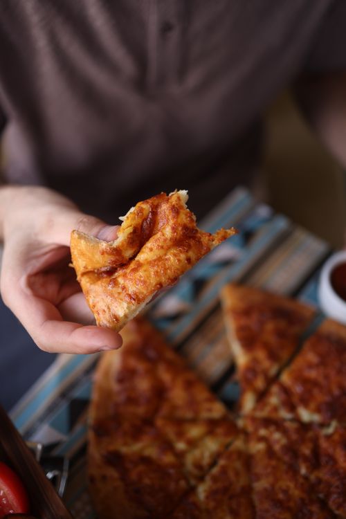 Free A warm, cheesy slice of pizza being held above the pie, perfect for lunch or dinner. Stock Photo