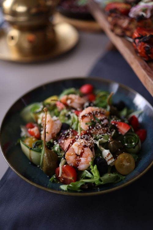 Free A vibrant prawn salad featuring cherry tomatoes and caper berries, surrounded by fresh greens. Stock Photo