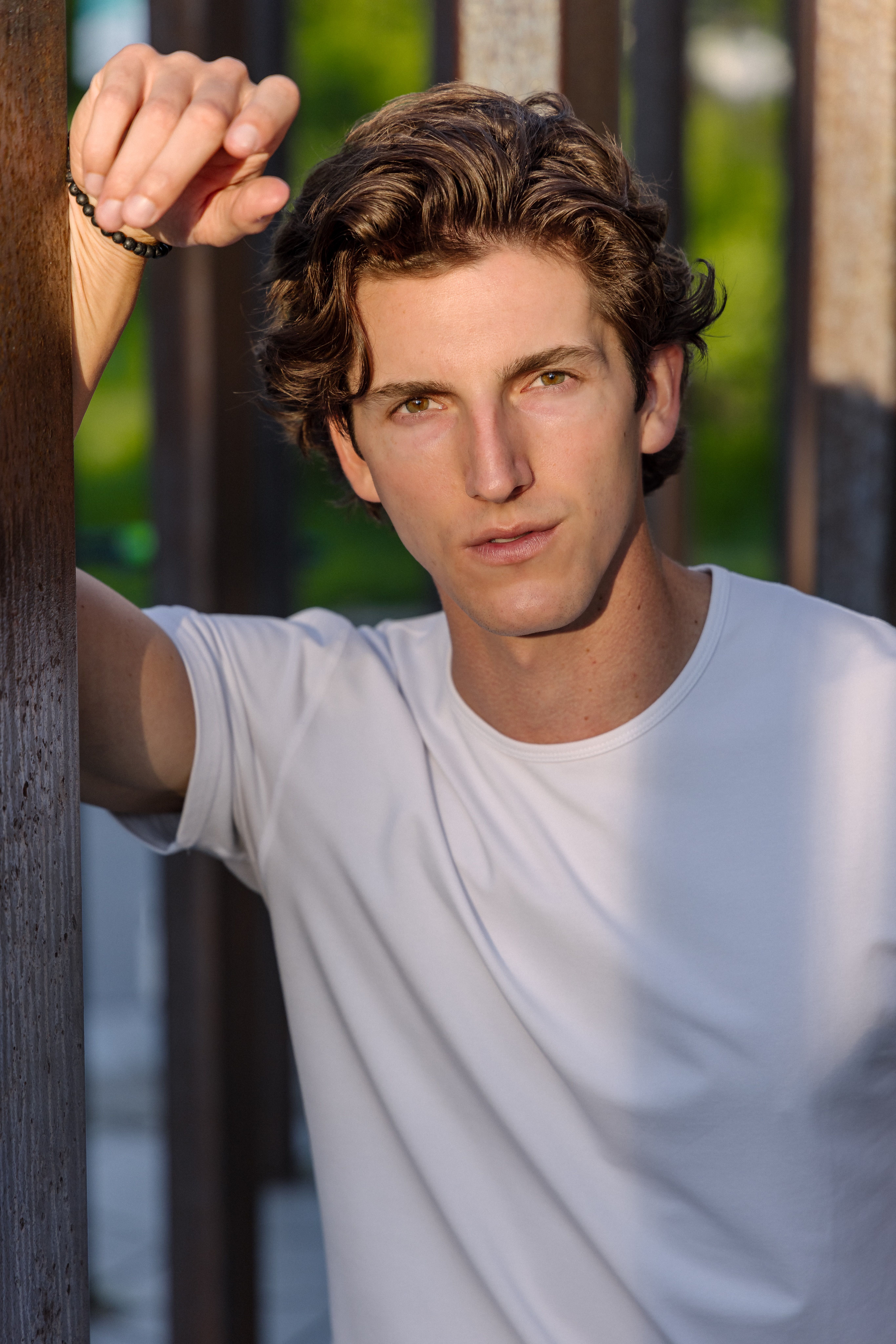 Portrait of a young man in a casual white shirt, exuding confidence in an urban summer setting.