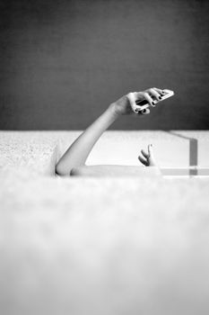Artistic photo capturing a minimalist scene in black and white, featuring a person's arm with a smartphone.