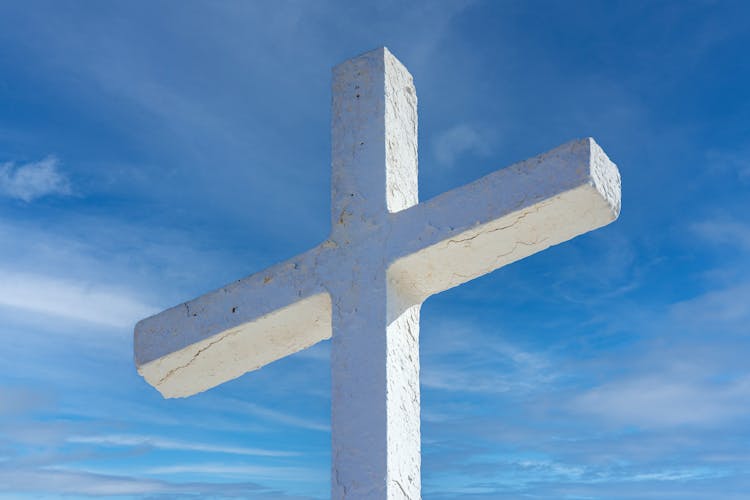 A White Cross On A White Rock With A Blue Sky